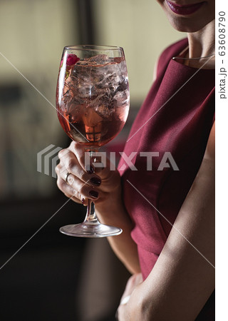 woman holds relaxing alcoholic pink coctail with a woman holds relaxing alcoholic pink coctail with a 63608790
