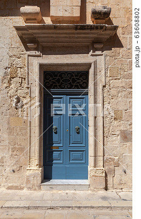 Vintage blue wooden door in yellow stone wall 63608802