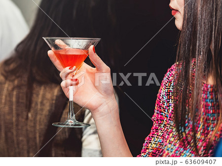 young woman holds drink in a bar young woman holds drink in a bar 63609407