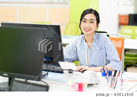 オフィスで笑顔で仕事する女性社員 63611916