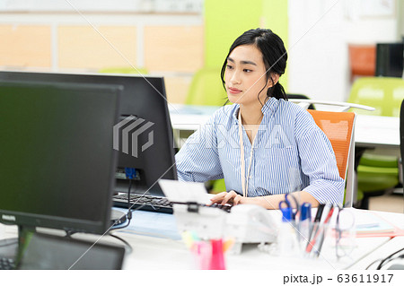 オフィスで真剣に仕事をする女性社員 63611917