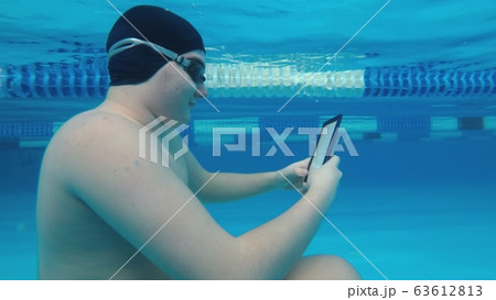 The guy is reading an electronic book underwater. The guy is reading an electronic book underwater. 63612813