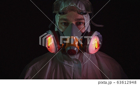 Man in protective costume suit, gas protect medical spray paint mask. Doctor in respirator. Concept health virus coronavirus epidemic. Man in protective costume suit, gas protect medical spray paint mask. Doctor in respirator. Concept health virus coronavirus epidemic. 63612948