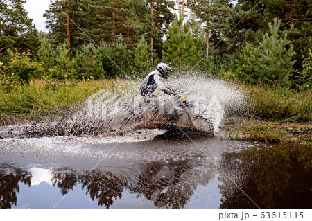 motocross rider riding a puddle in forest trail 63615115