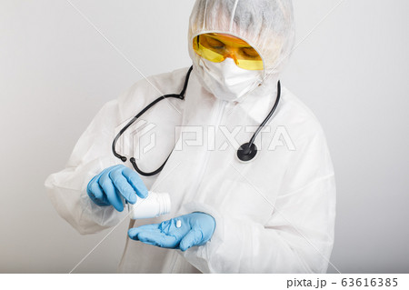 Doctor in anti-epidemic suit holds bottle with 63616385