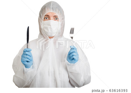 Woman in anti-epidemic suit holds knife and fork Woman in anti-epidemic suit holds knife and fork 63616393