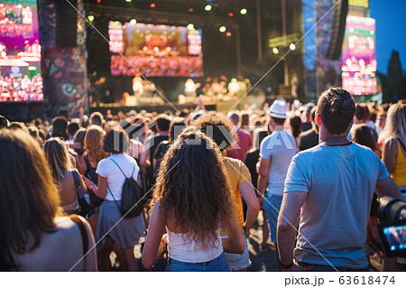 Rear view of group of young friends at summer festival. Rear view of group of young friends at summer festival. 63618474