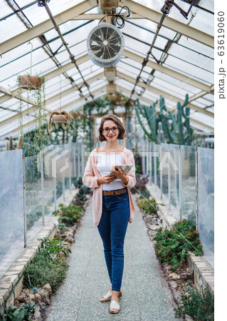 Woman researcher standing in greenhouse, using tablet. Woman researcher standing in greenhouse, using tablet. 63619060