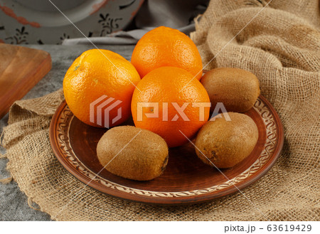 Tropical oranges and kiwies in a decorated plate. Tropical oranges and kiwies in a decorated plate. 63619429