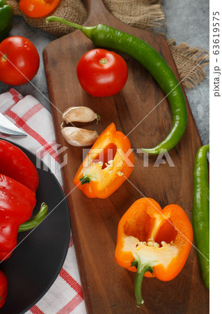 Chilies, yellow peppers, tomat and garlics on a wooden board. Top view. 63619575