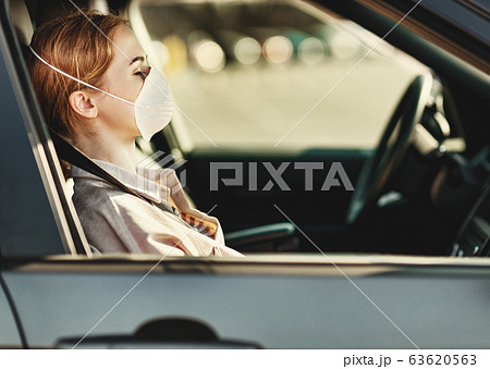 Woman in medical mask sitting in car. 63620563