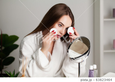 Cute young woman puts makeup on the face in the bathroom 63623464
