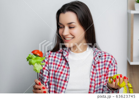 Cute woman makes a choice between healthy and harmful food 63623745