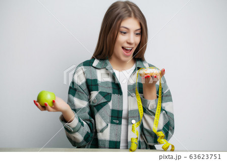 Cute woman makes a choice between healthy and harmful food 63623751