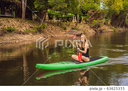SUP Stand up paddle board woman paddle boarding on lake standing happy on paddleboard on blue water SUP Stand up paddle board woman paddle boarding on lake standing happy on paddleboard on blue water 63625355