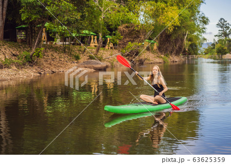 SUP Stand up paddle board woman paddle boarding on lake standing happy on paddleboard on blue water SUP Stand up paddle board woman paddle boarding on lake standing happy on paddleboard on blue water 63625359