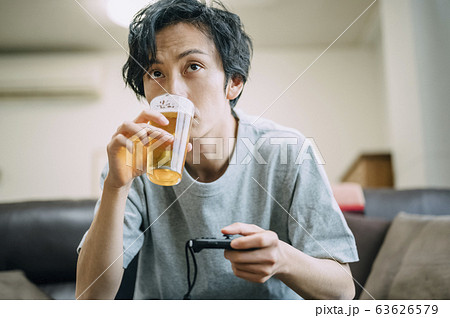部屋でゲームをする男性 63626579