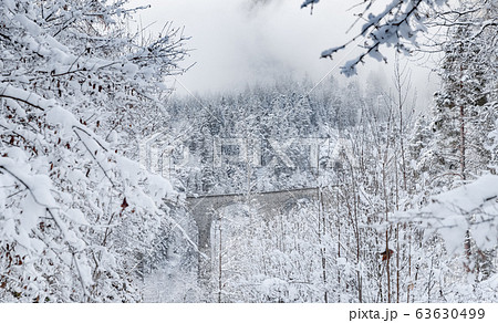 The Landwasser Viaduct with Railway without famous train at winter, landmark of Switzerland, snowing, river and mountains 63630499