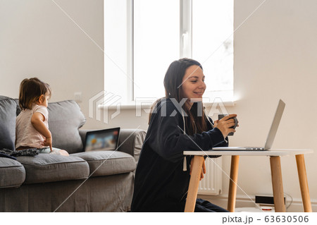 Young woman working from home. Child watching cartoons on the tablet. Work from home Young woman working from home. Child watching cartoons on the tablet. Work from home 63630506