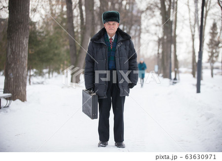 An eldery man with case standing outdoors in winter park An eldery man with case standing outdoors in winter park 63630971
