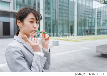 電子タバコを吸う若いビジネスウーマン 電子タバコを吸う若いビジネスウーマン 63631854