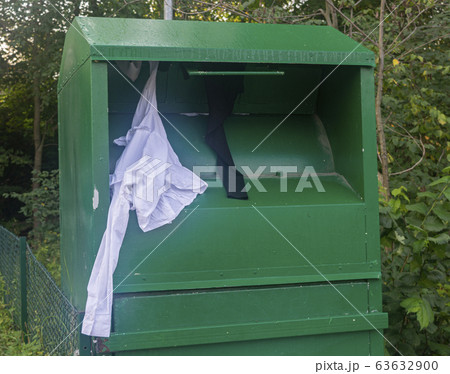 green container for clothes, clothes sticking out of the container 63632900