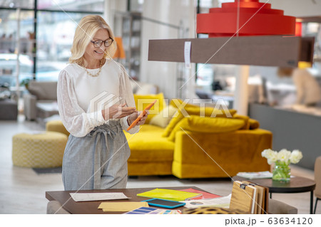 Woman designer standing near the table with a tablet in hands. 63634120