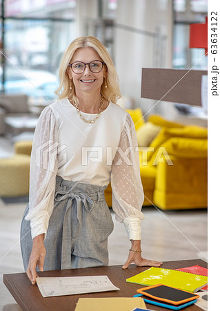 Joyful elegant woman standing near her desk. 63634122