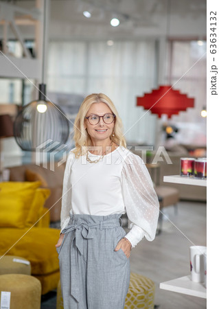 Standing joyful woman in a white blouse, hands in pockets. 63634132