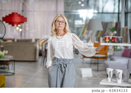 Serious woman with glasses standing in a large hall. 63634133