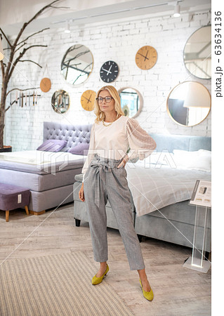 Woman in gray trousers and yellow shoes standing near the beds. 63634136