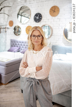 Successful woman in glasses and a light blouse is indoors. 63634137