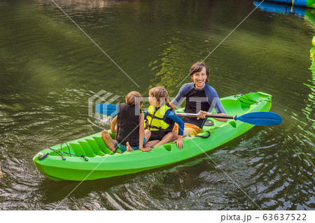 A man and two boys in a kayak on the river. Happy childhood 63637522