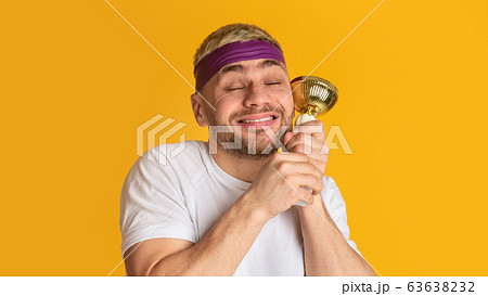 Happy millennial man holds reward and close his eyes 63638232