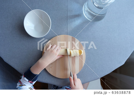 a 6 year old child cutting a ripe banana on grey a 6 year old child cutting a ripe banana on grey 63638878
