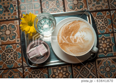 cappuccino in a white cup on a white saucer with two pieces of marshmallow cappuccino in a white cup on a white saucer with two pieces of marshmallow 63641870