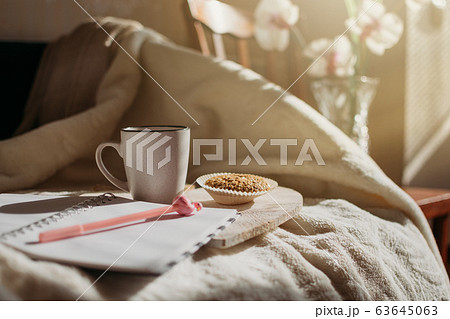 Morning routine, Miracle Morning, new day concept. Best ritual and habits. Cup of coffee, whole grain cookies, open notepad on wooden tray on the bed in the sun. 63645063