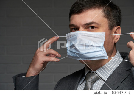a man puts a mask on his face for antivirus a man puts a mask on his face for antivirus 63647917