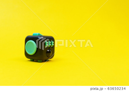 Black and green fidget cube on yellow background, minimal concept, copyspace. 63650234
