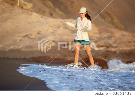 Young woman having fun at ocean beach on vacation Young woman having fun at ocean beach on vacation 63651435