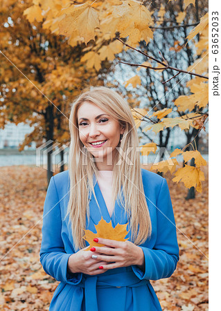 beautiful smiling mature woman with autumn maple leaves in hands in park 63652033