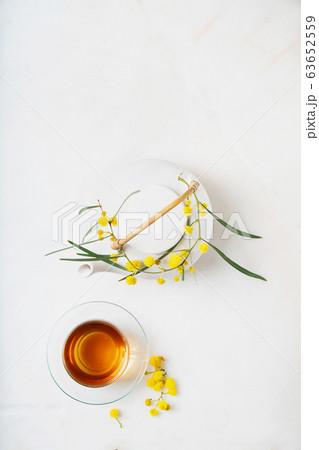 Cup of herbal tea. Mimosa branch decoration. 63652559