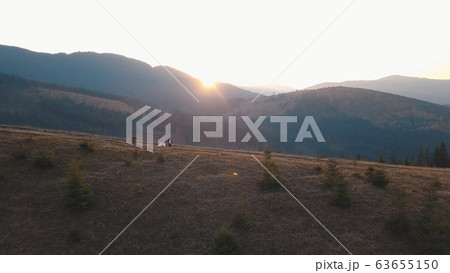 Newlyweds running on a high slope of the mountain. Groom and bride. Aerial view Newlyweds running on a high slope of the mountain. Groom and bride. Aerial view 63655150