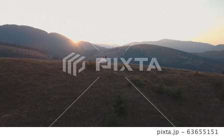 Newlyweds running on a high slope of the mountain. Groom and bride. Aerial view Newlyweds running on a high slope of the mountain. Groom and bride. Aerial view 63655151