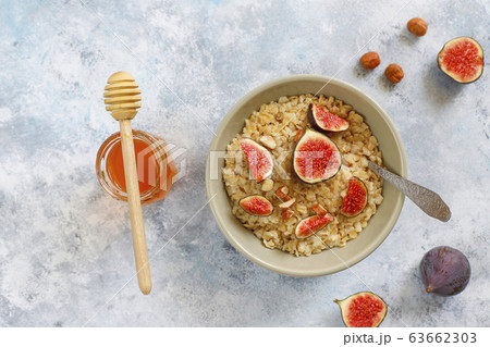 Oatmeal porridge with red figs and walnuts,honey in a bowl, above view on light background Oatmeal porridge with red figs and walnuts,honey in a bowl, above view on light background 63662303