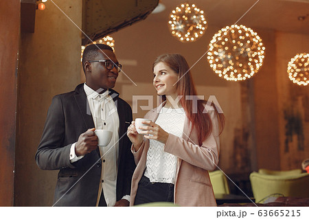 Internationals people standing in a cafe and drinking a coffee Internationals people standing in a cafe and drinking a coffee 63665215