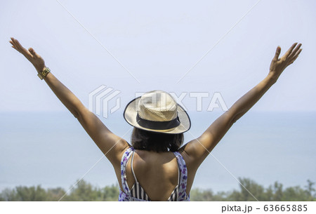 The image behind Asian women raise their arms and wear a hat background sea. The image behind Asian women raise their arms and wear a hat background sea. 63665885
