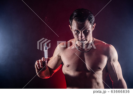 Bodybuilder holding big syringe with injection. concept of steroid in the sport and addiction  63666836