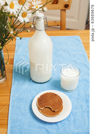 Simply stylish wooden kitchen with bottle of milk and glass on table, summer flowers camomile, healthy foog moring concept Simply stylish wooden kitchen with bottle of milk and glass on table, summer flowers camomile, healthy foog moring concept 63669676