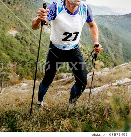 man athlete uphill mountain with trekking poles 63671491